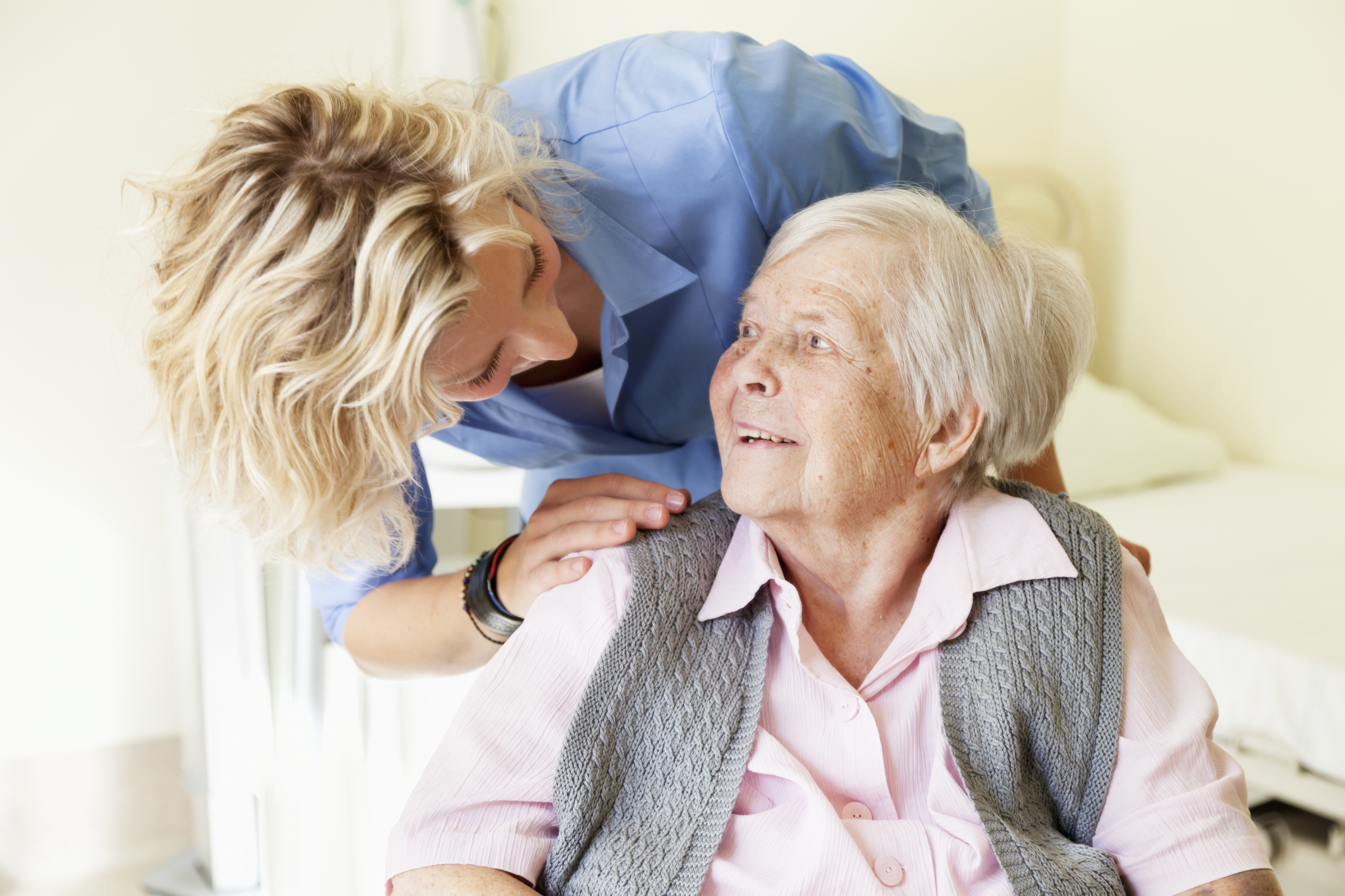 young nurse smiling at senior patient in hospital